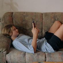 Teenage boy on phone lying on lounge