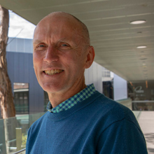A/Prof John Ferguson - researcher in blue sweater outside the HMRI building smiling at camera