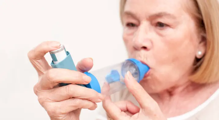 Woman holing asthma puffer and spacer