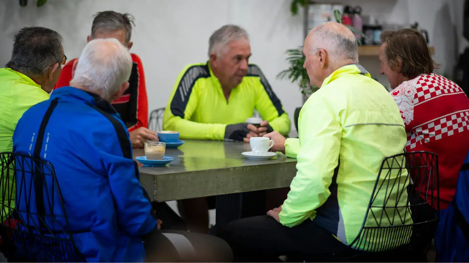 group of male cyclists talking at a cafe