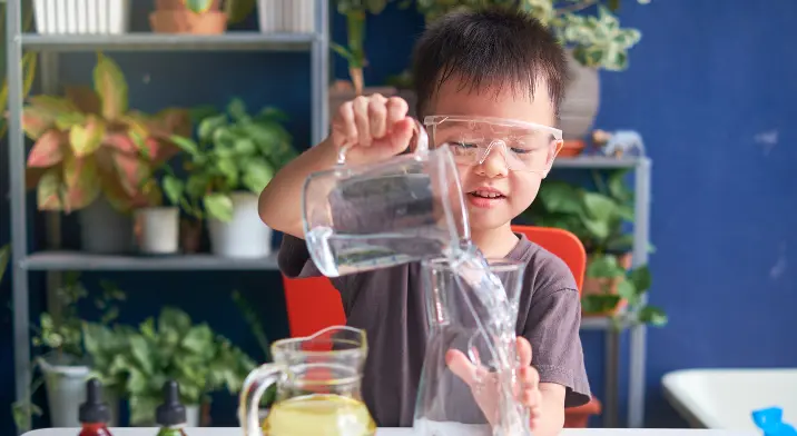 Young boy pouring water into a beaker