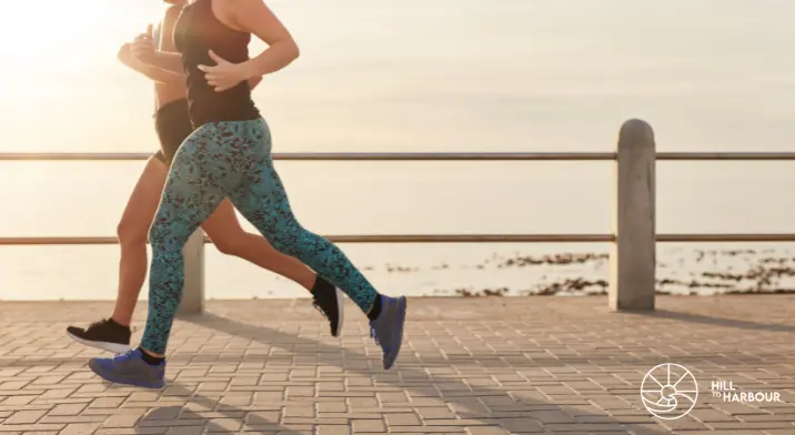 Two females running along beach front